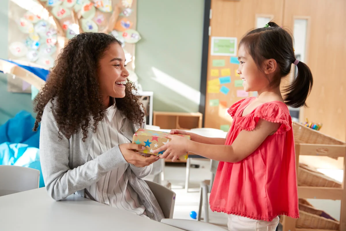 A young girl giving a gift to a smiling support worker