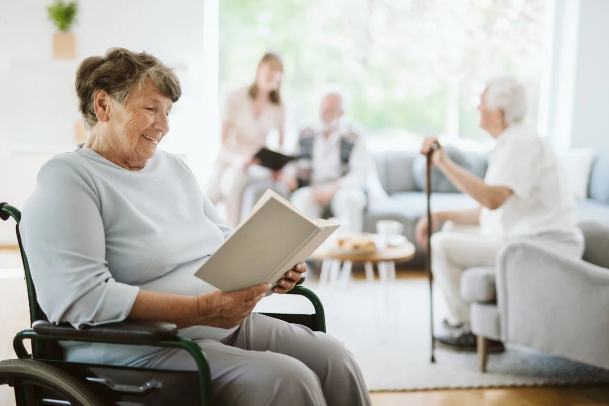 A smiling woman in a wheelchair reading a book